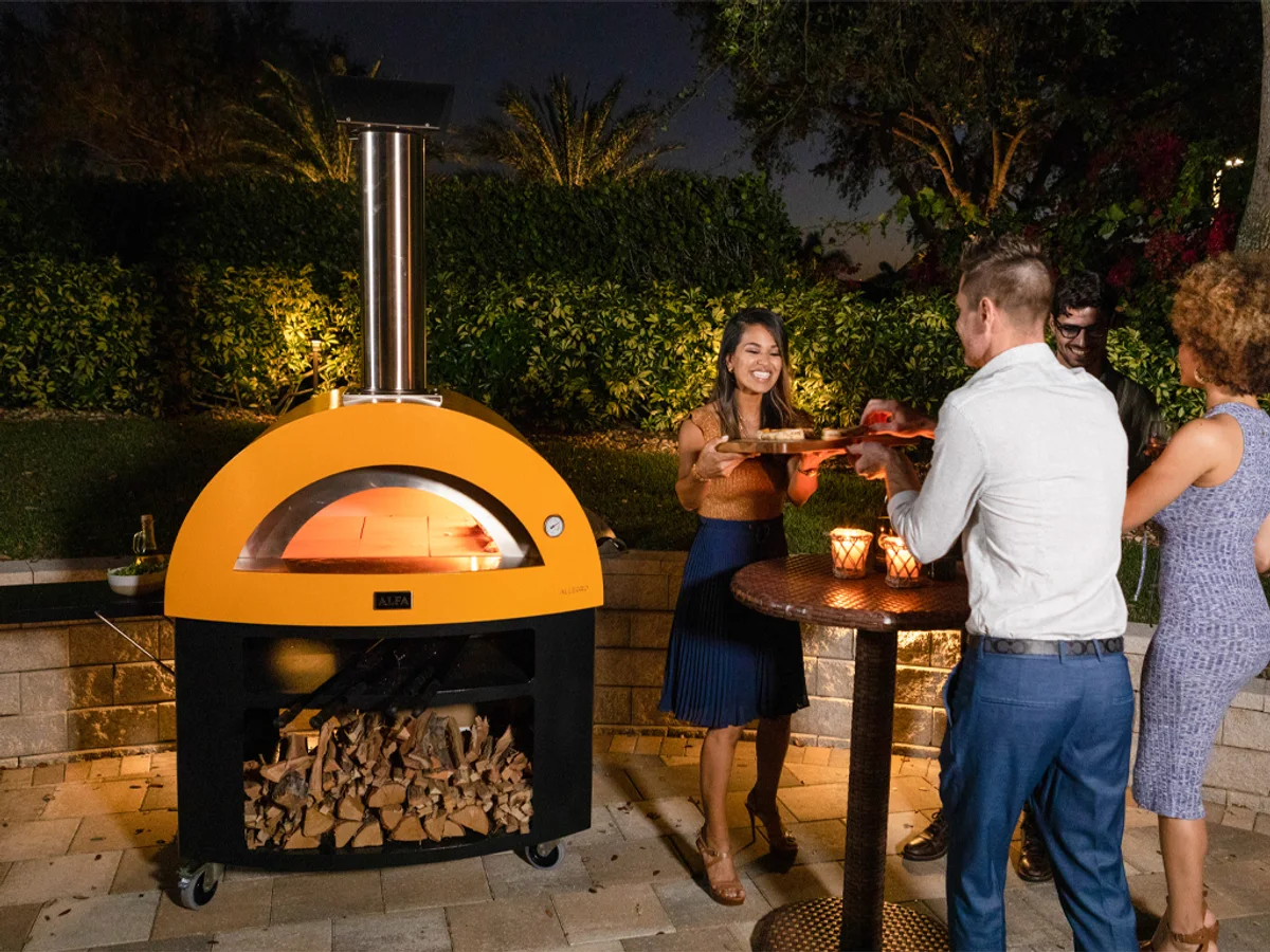Four à pizza Alfa Forni Moderno 5 Pizze allumé, en soirée, sur une terrasse