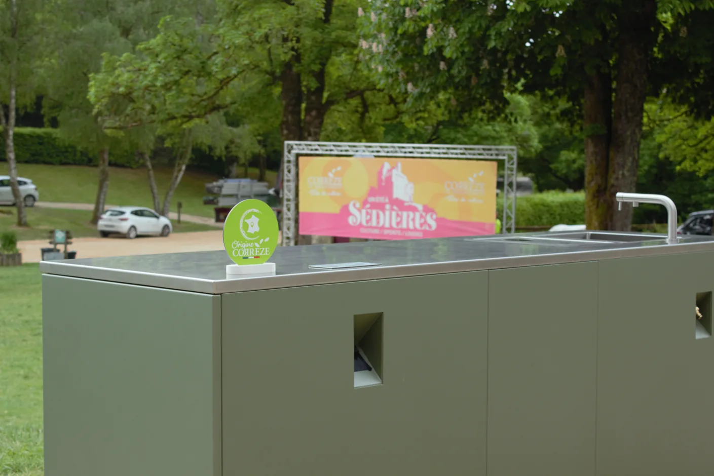 Cuisine d'extérieur mobile ROLYX posée sur l'herbe d'un parc, plan de travail en inox et mitigeur, sans dalle ni raccordement fixe