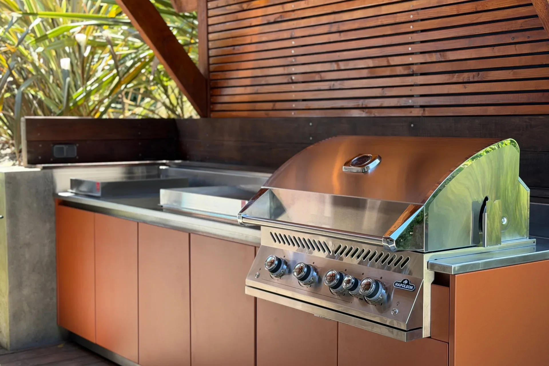 Le barbecue à gaz Napoleon encastré dans le plan inox de la cuisine EKZALT orange