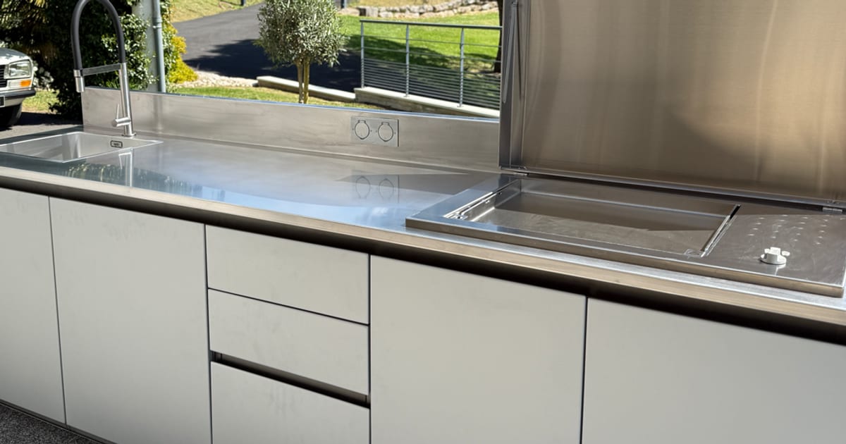 Plan de travail en inox 316L d'une cuisine d'extérieur X-PRESS : évier encastré, prise étanche et plancha capot ouvert