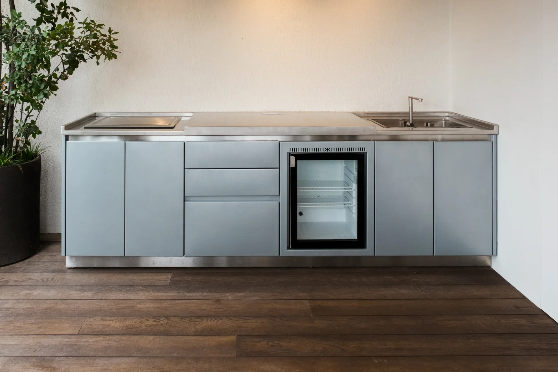 La cuisine SOLSTYS vue de face, capots ouverts : teppanyaki, plan en inox 316L, réfrigérateur encastré et évier